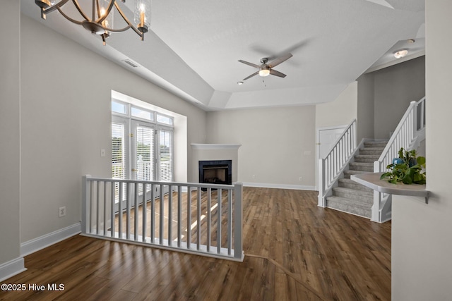 unfurnished living room featuring wood finished floors, a chandelier, ceiling fan, and a fireplace