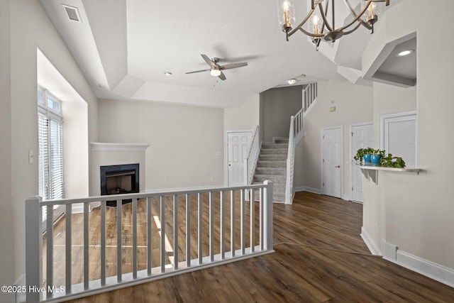 hallway featuring baseboards, wood finished floors, stairway, and a chandelier