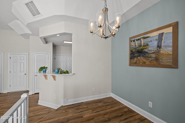 empty room featuring dark wood-type flooring, a chandelier, baseboards, and vaulted ceiling