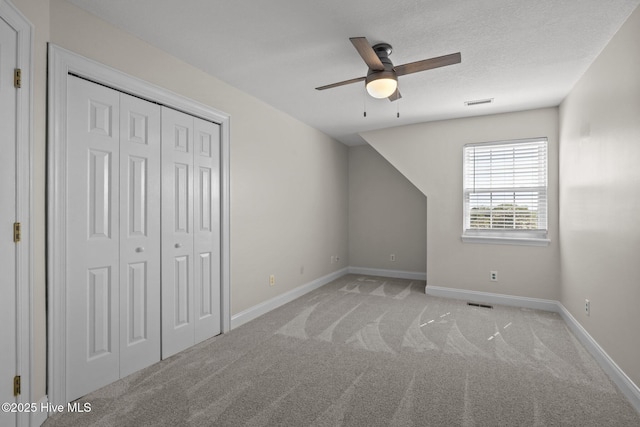 unfurnished bedroom with light colored carpet, baseboards, a closet, and ceiling fan