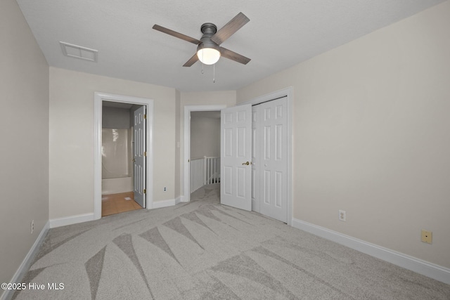 unfurnished bedroom with carpet floors, baseboards, a closet, connected bathroom, and ceiling fan