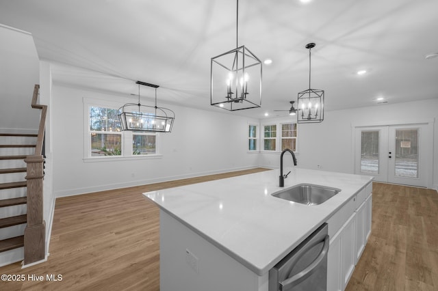 kitchen with a sink, dishwasher, a chandelier, white cabinets, and light wood-style floors