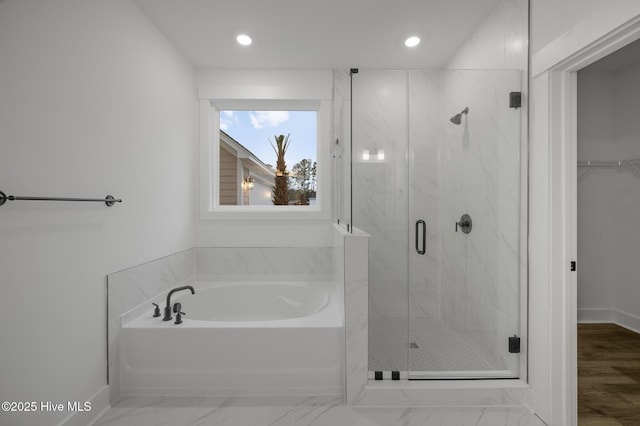 full bathroom featuring a marble finish shower, a garden tub, recessed lighting, a walk in closet, and baseboards