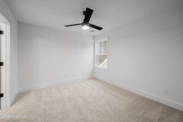 carpeted spare room featuring ceiling fan and baseboards