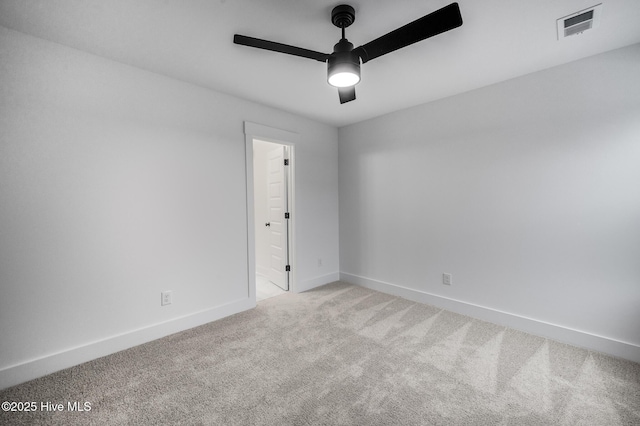spare room with a ceiling fan, light carpet, and baseboards