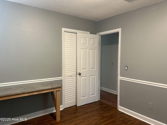 3414 Middle Sound Loop Rd, Wilmington, NC 28411 - unfurnished bedroom featuring dark wood finished floors, a closet, baseboards, and a textured ceiling