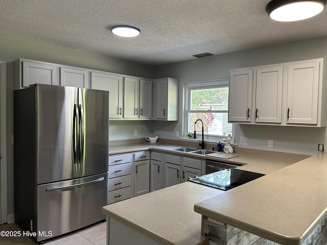 3414 Middle Sound Loop Rd, Wilmington, NC 28411 - kitchen with freestanding refrigerator, a sink, a peninsula, a textured ceiling, and light countertops