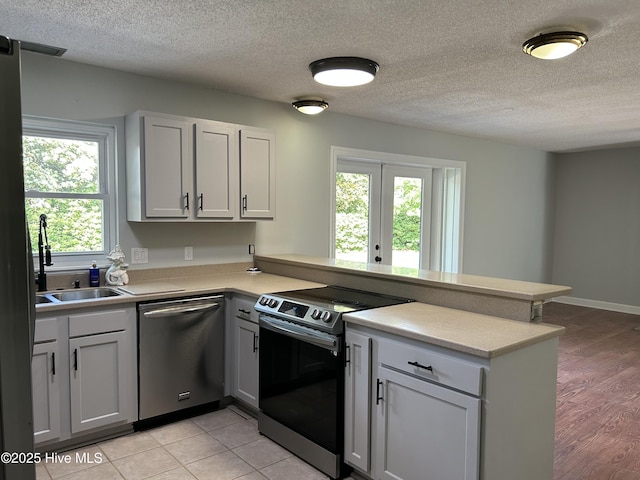 3414 Middle Sound Loop Rd, Wilmington, NC 28411 - kitchen with appliances with stainless steel finishes, a peninsula, a sink, light countertops, and a textured ceiling