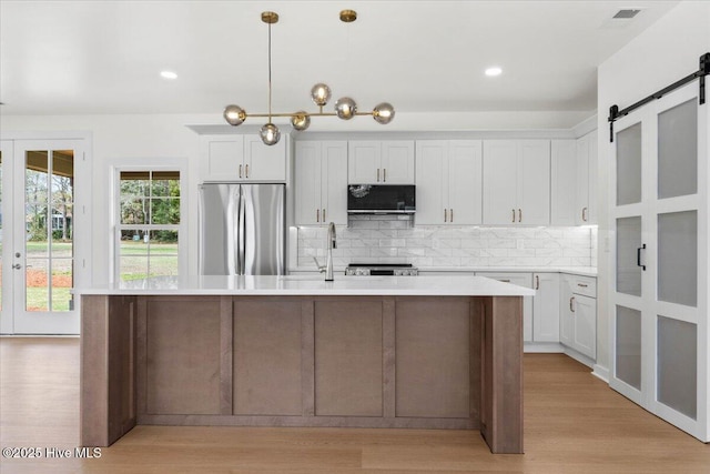 355 S Middleton Dr NW, Calabash, NC 28467 - kitchen featuring freestanding refrigerator, black microwave, a barn door, decorative backsplash, and light countertops