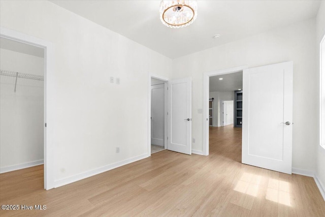355 S Middleton Dr NW, Calabash, NC 28467 - unfurnished bedroom with a walk in closet, light wood-style floors, baseboards, a chandelier, and a closet