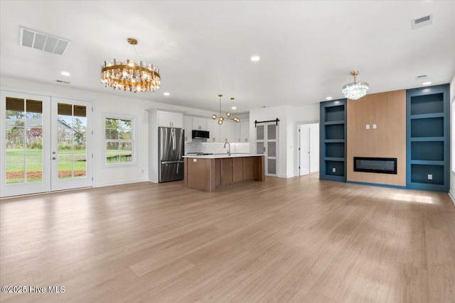 355 S Middleton Dr NW, Calabash, NC 28467 - kitchen with freestanding refrigerator, a chandelier, open floor plan, light countertops, and light wood-type flooring