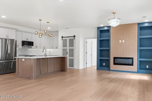 355 S Middleton Dr NW, Calabash, NC 28467 - kitchen featuring stainless steel appliances, a chandelier, built in shelves, light countertops, and light wood-style flooring