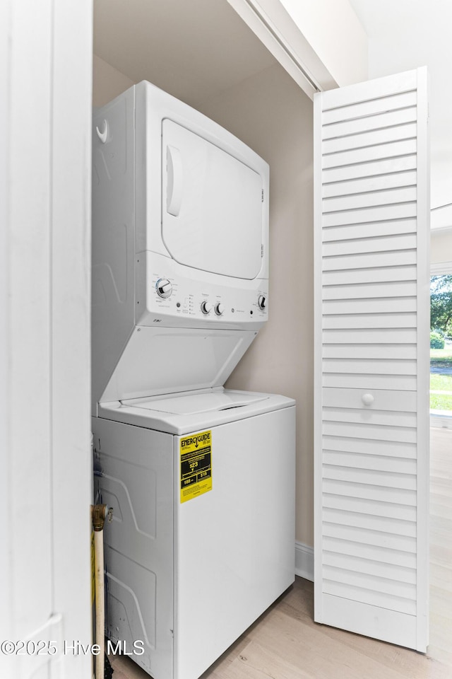 washroom with stacked washer / drying machine and light wood-type flooring