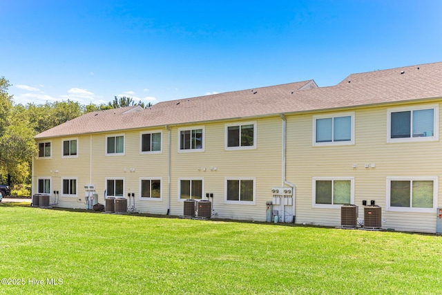 rear view of property with cooling unit and a yard