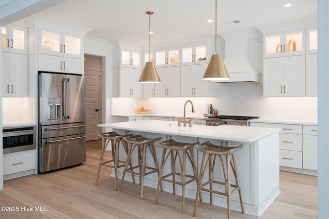kitchen with appliances with stainless steel finishes, light wood-style flooring, light countertops, a breakfast bar area, and recessed lighting