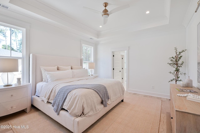 bedroom with a tray ceiling, recessed lighting, light wood-type flooring, ceiling fan, and baseboards