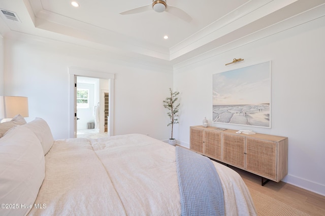 bedroom featuring light wood finished floors, a tray ceiling, crown molding, recessed lighting, and baseboards