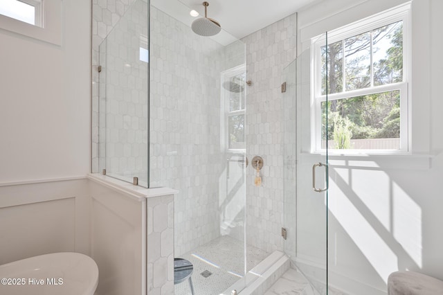 bathroom featuring a stall shower, plenty of natural light, a freestanding bath, and marble look tile flooring