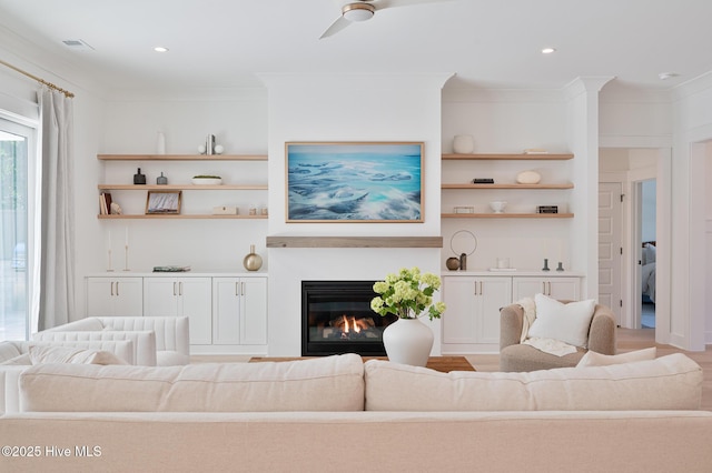 living room with a glass covered fireplace, crown molding, ceiling fan, wood finished floors, and recessed lighting