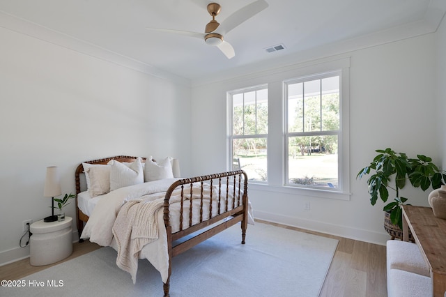 bedroom featuring wood finished floors, baseboards, crown molding, and ceiling fan