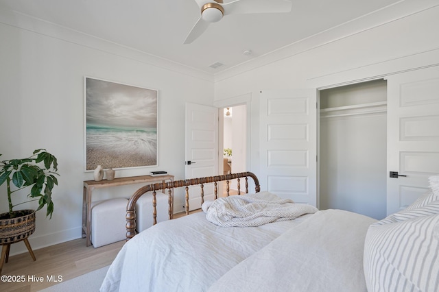 bedroom with light wood-style floors, ornamental molding, baseboards, a closet, and a ceiling fan