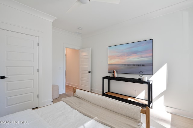 bedroom featuring wood finished floors, ornamental molding, and baseboards
