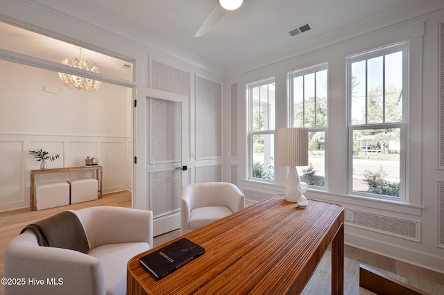 home office with a decorative wall, wood finished floors, a chandelier, and ceiling fan
