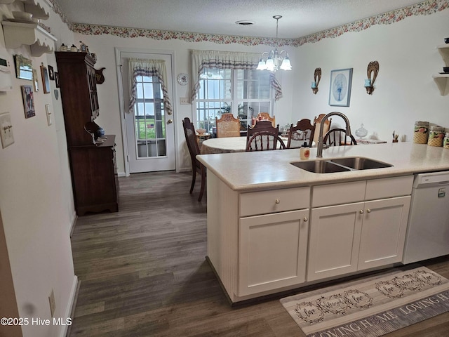 kitchen with a sink, dishwasher, a chandelier, dark wood-type flooring, and white cabinetry