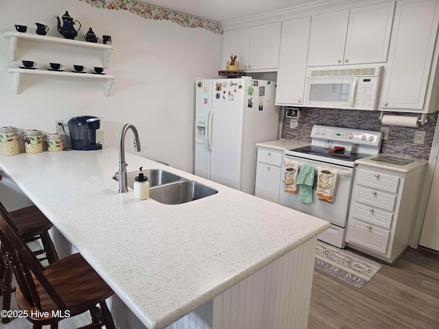 kitchen featuring white appliances, a sink, a peninsula, and light countertops