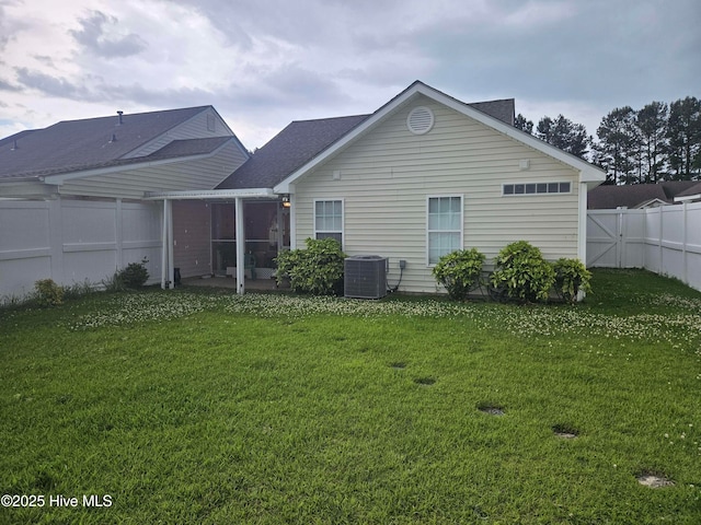 rear view of property featuring a sunroom, cooling unit, and a shingled roof