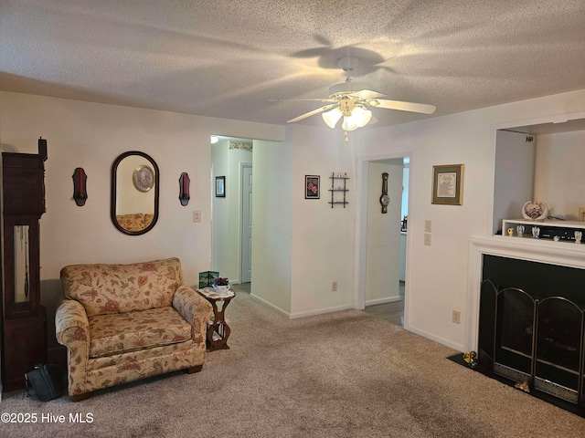 living room with ceiling fan, carpet floors, a textured ceiling, and baseboards