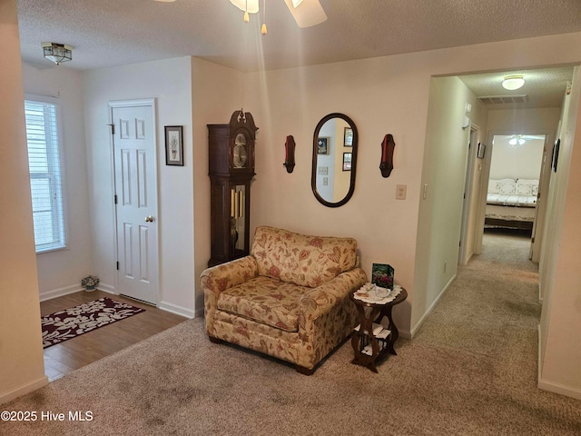 sitting room featuring carpet floors, ceiling fan, a textured ceiling, and baseboards