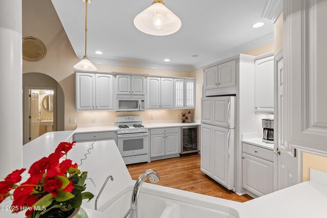 kitchen with white range with gas cooktop, wine cooler, decorative light fixtures, built in refrigerator, and light countertops