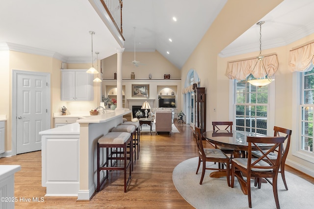 dining space featuring light wood finished floors, a fireplace, built in features, recessed lighting, and baseboards