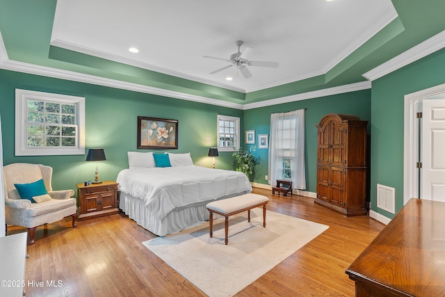 bedroom with light wood finished floors, a raised ceiling, crown molding, baseboards, and recessed lighting