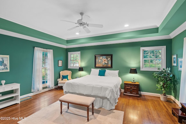 bedroom featuring multiple windows, ornamental molding, wood finished floors, baseboards, and ceiling fan