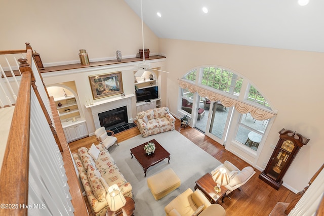 living area featuring high vaulted ceiling, wood finished floors, a fireplace, a ceiling fan, and recessed lighting