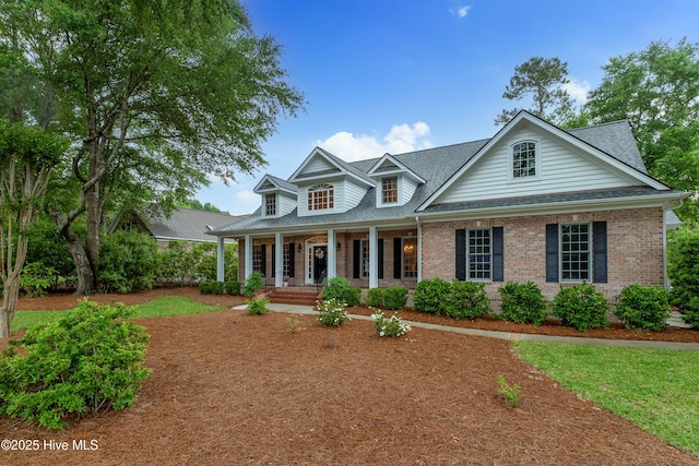 view of front of house featuring a porch, brick siding, and roof with shingles