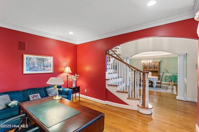 living room with arched walkways, a chandelier, wood finished floors, stairs, and baseboards