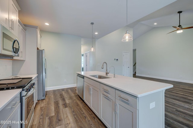 kitchen featuring stainless steel appliances, a sink, dark wood-style flooring, a center island with sink, and light countertops