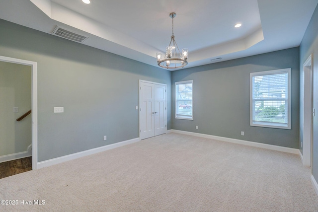 spare room featuring a chandelier, baseboards, a tray ceiling, light colored carpet, and recessed lighting