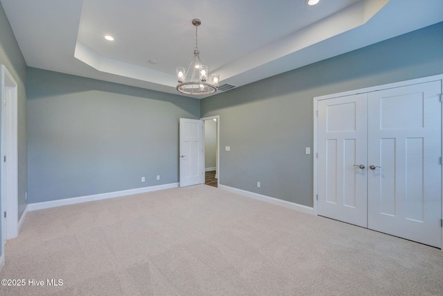 unfurnished bedroom featuring carpet, a chandelier, baseboards, a raised ceiling, and recessed lighting