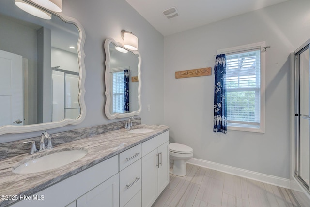full bath with baseboards, a shower with door, double vanity, and toilet