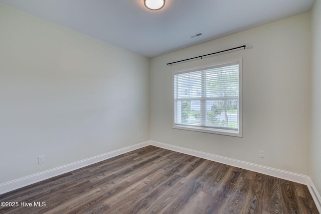 empty room featuring baseboards and dark wood-type flooring