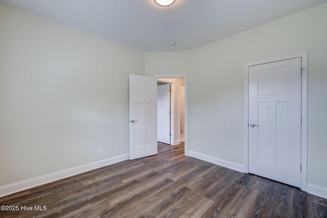 unfurnished bedroom featuring dark wood-type flooring and baseboards