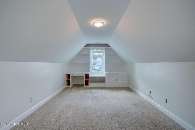 additional living space featuring vaulted ceiling, light colored carpet, and baseboards