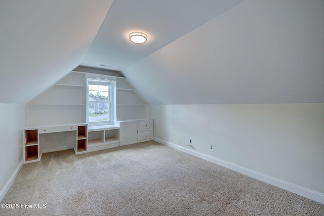 additional living space featuring vaulted ceiling, light colored carpet, and baseboards