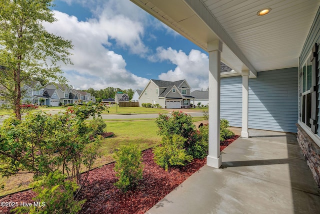 view of green lawn with a residential view and covered porch