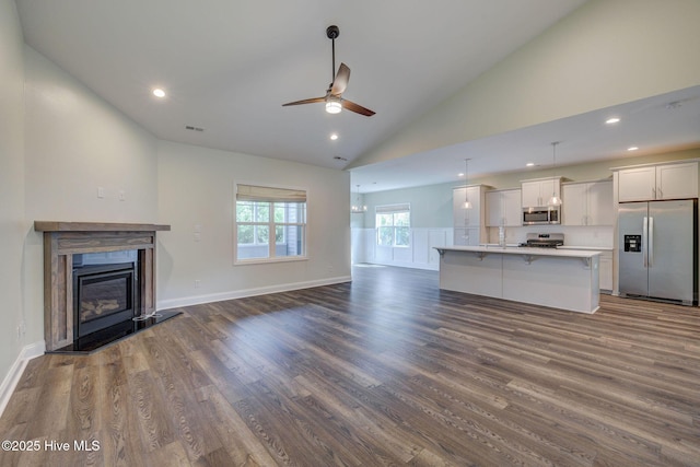 unfurnished living room featuring a ceiling fan, dark wood finished floors, a glass covered fireplace, recessed lighting, and baseboards