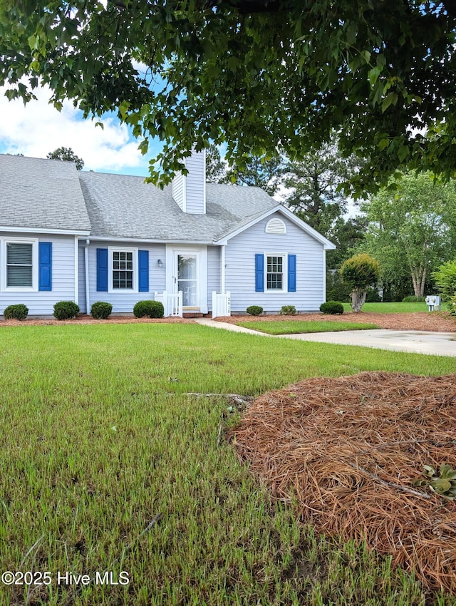 view of front of property featuring a front lawn, a chimney, and roof with shingles